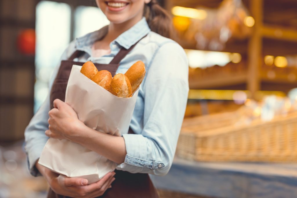 Young woman with baguettes in the bakery